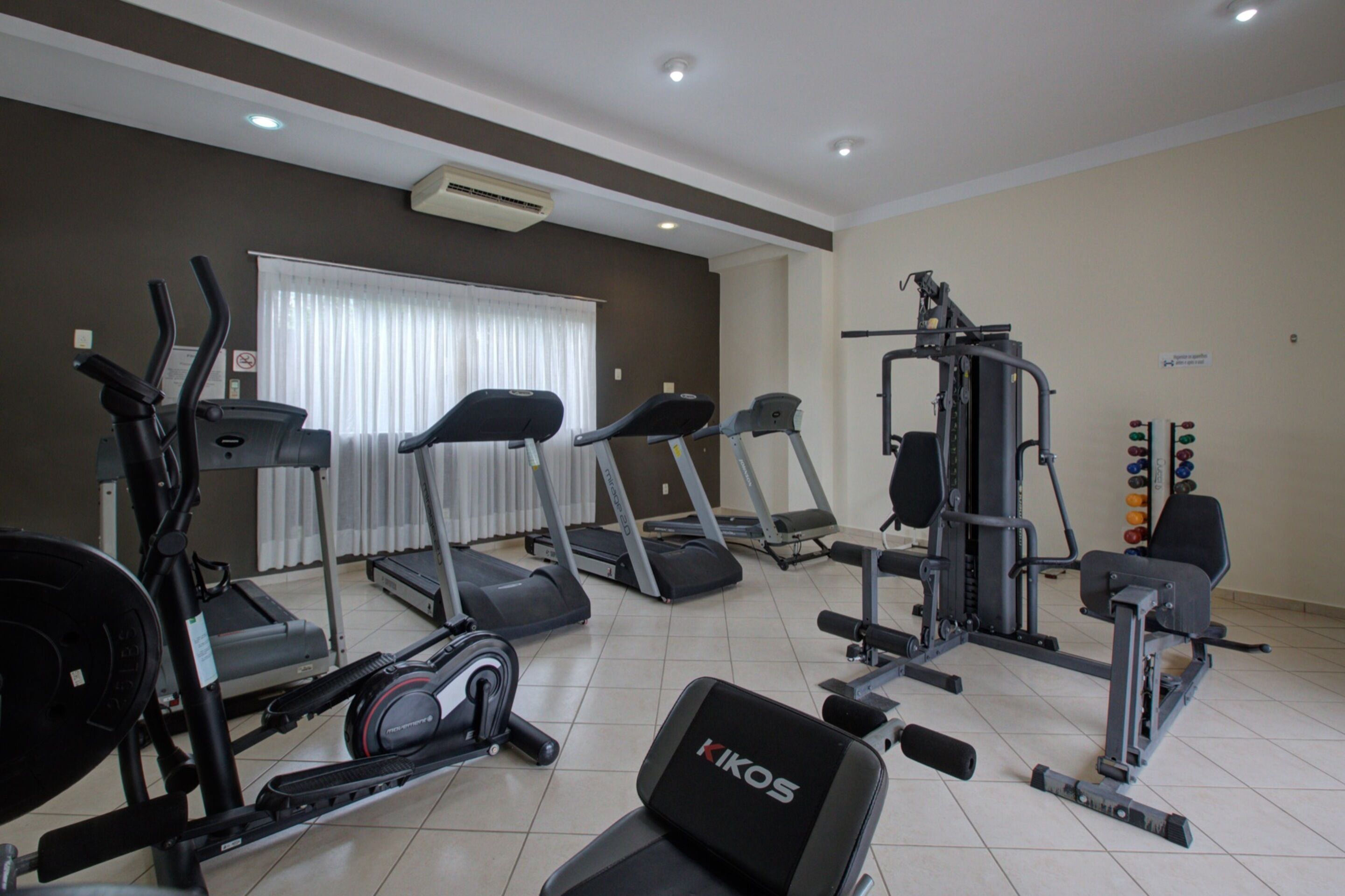 Un gimnasio con cintas de correr, elípticas y equipo de levantamiento de pesas.