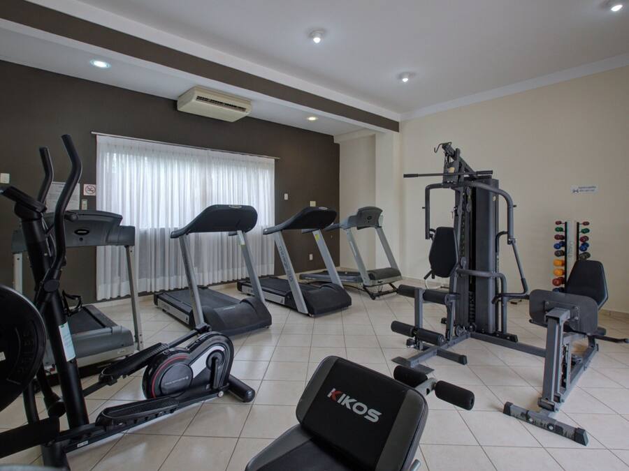 Un gimnasio con cintas de correr, elípticas y equipo de levantamiento de pesas.
