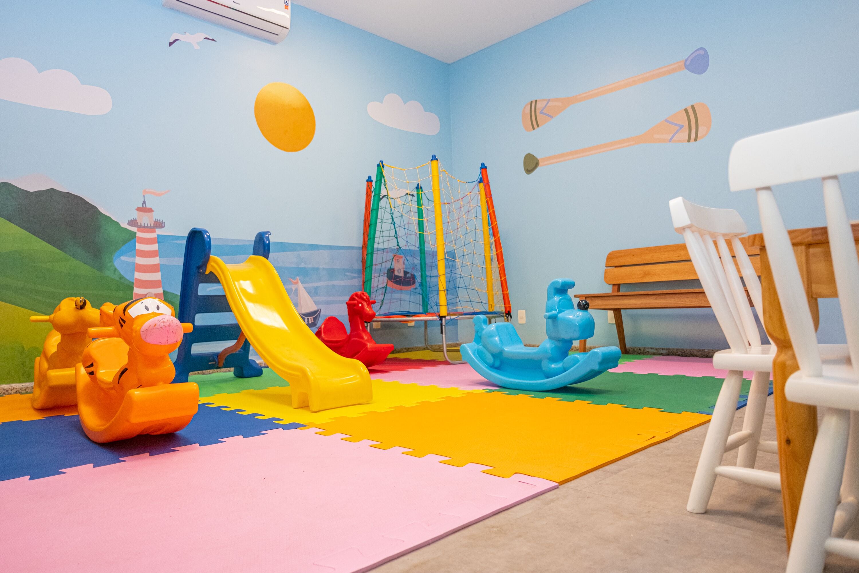 A playroom with a slide, climbing net, and various toys.