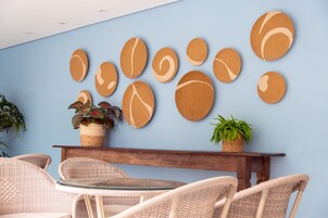 A room with wicker furniture, a wooden table, and a wall decorated with circular wooden art pieces.
