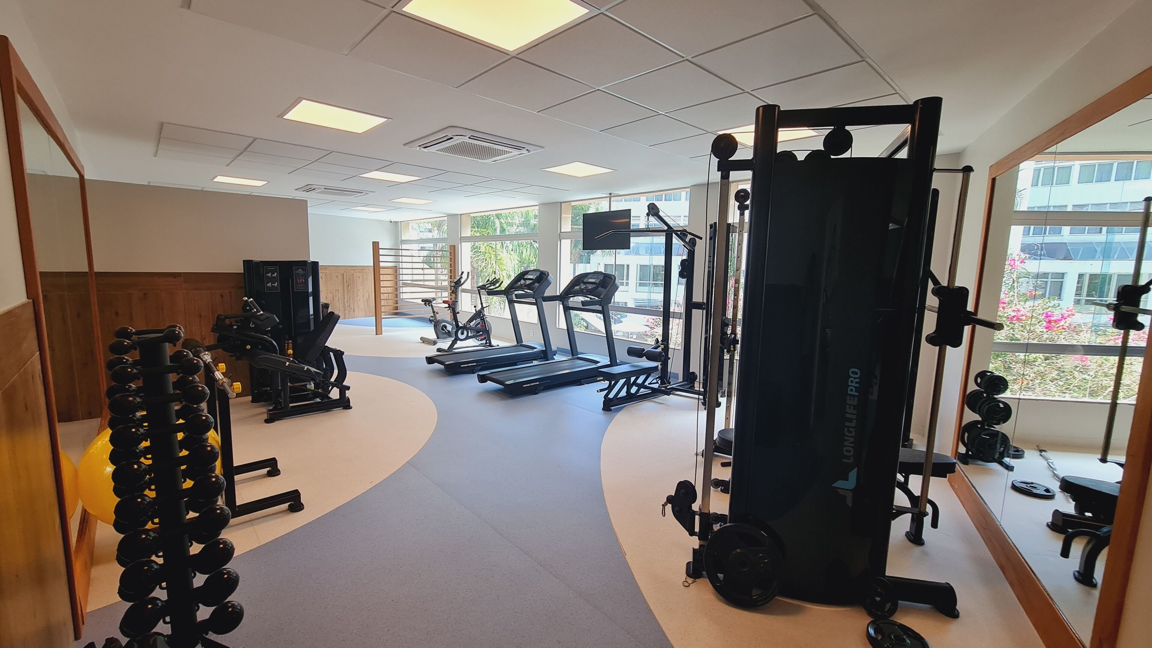 Une salle de sport équipée de tapis de course, d’appareils de musculation et d’un support à squats.