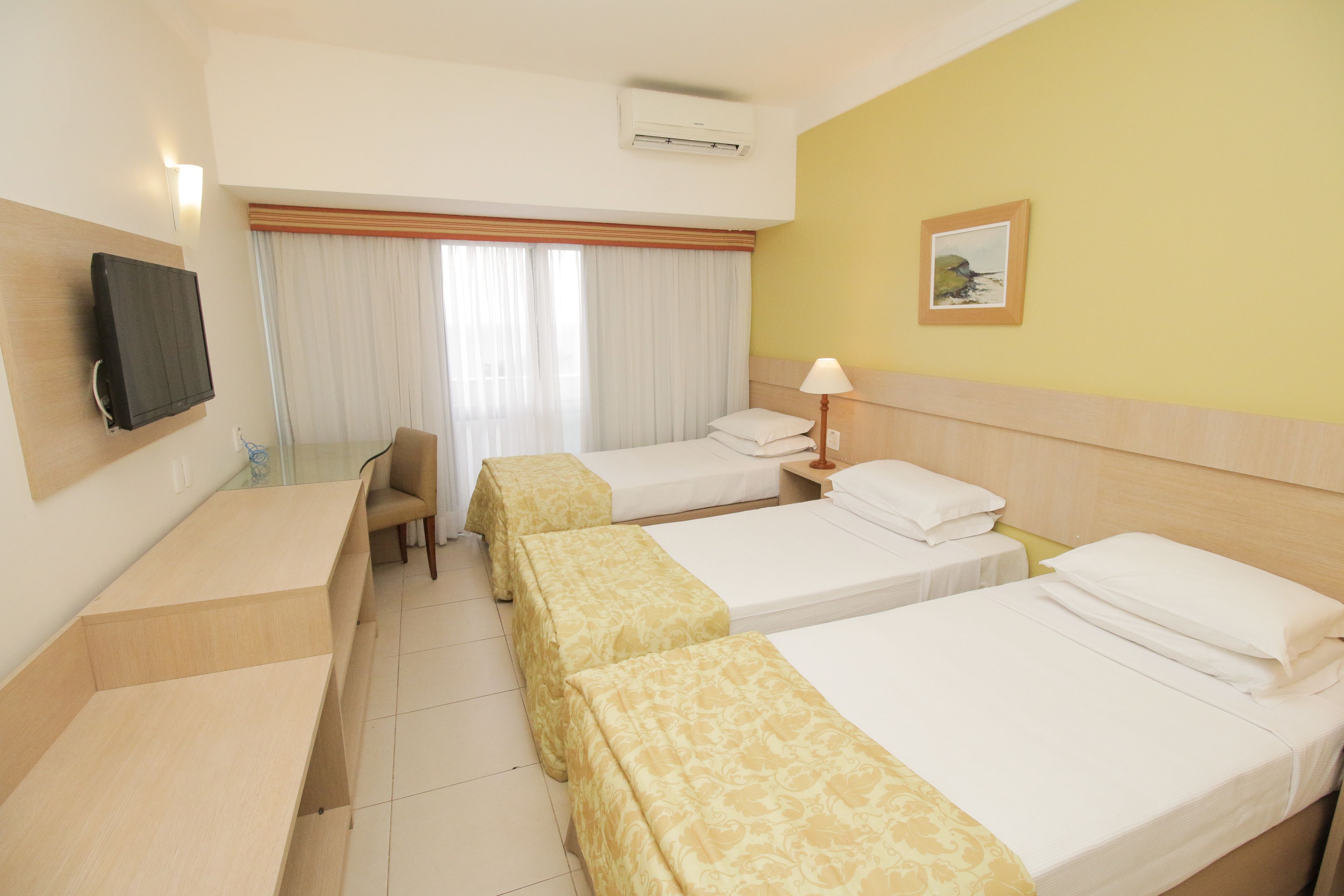 A hotel room with two beds, a desk, a chair, and a television.