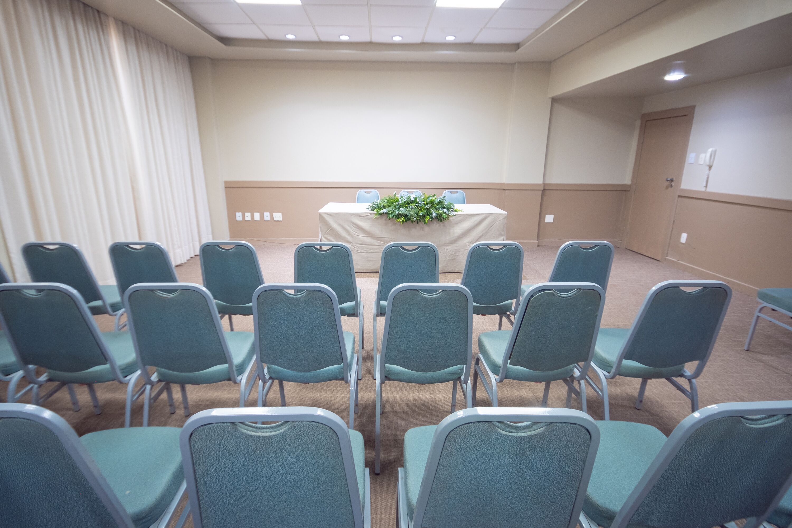 A conference room with a table, chairs, and a curtain.