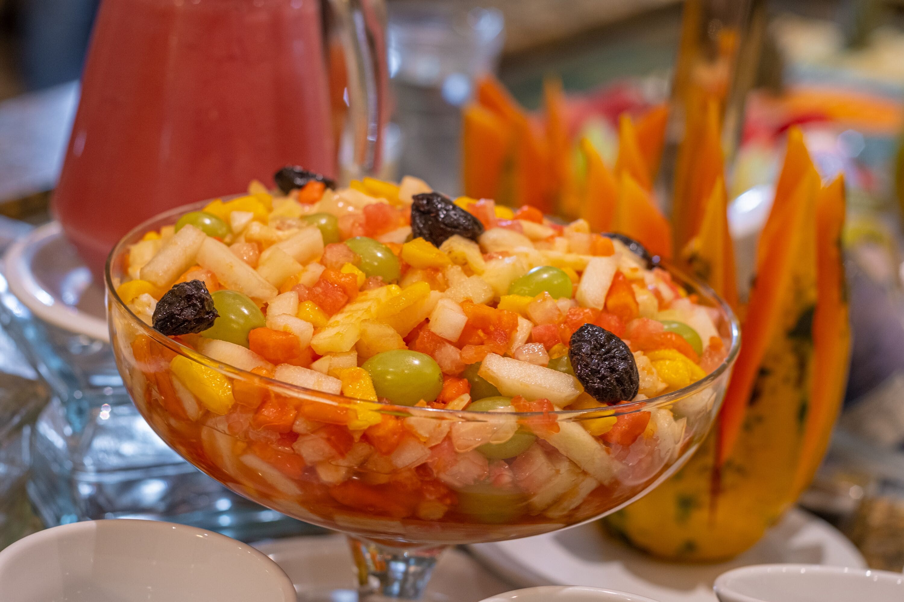 Ensalada de frutas en un tazón de vidrio con una variedad de frutas y pasas.