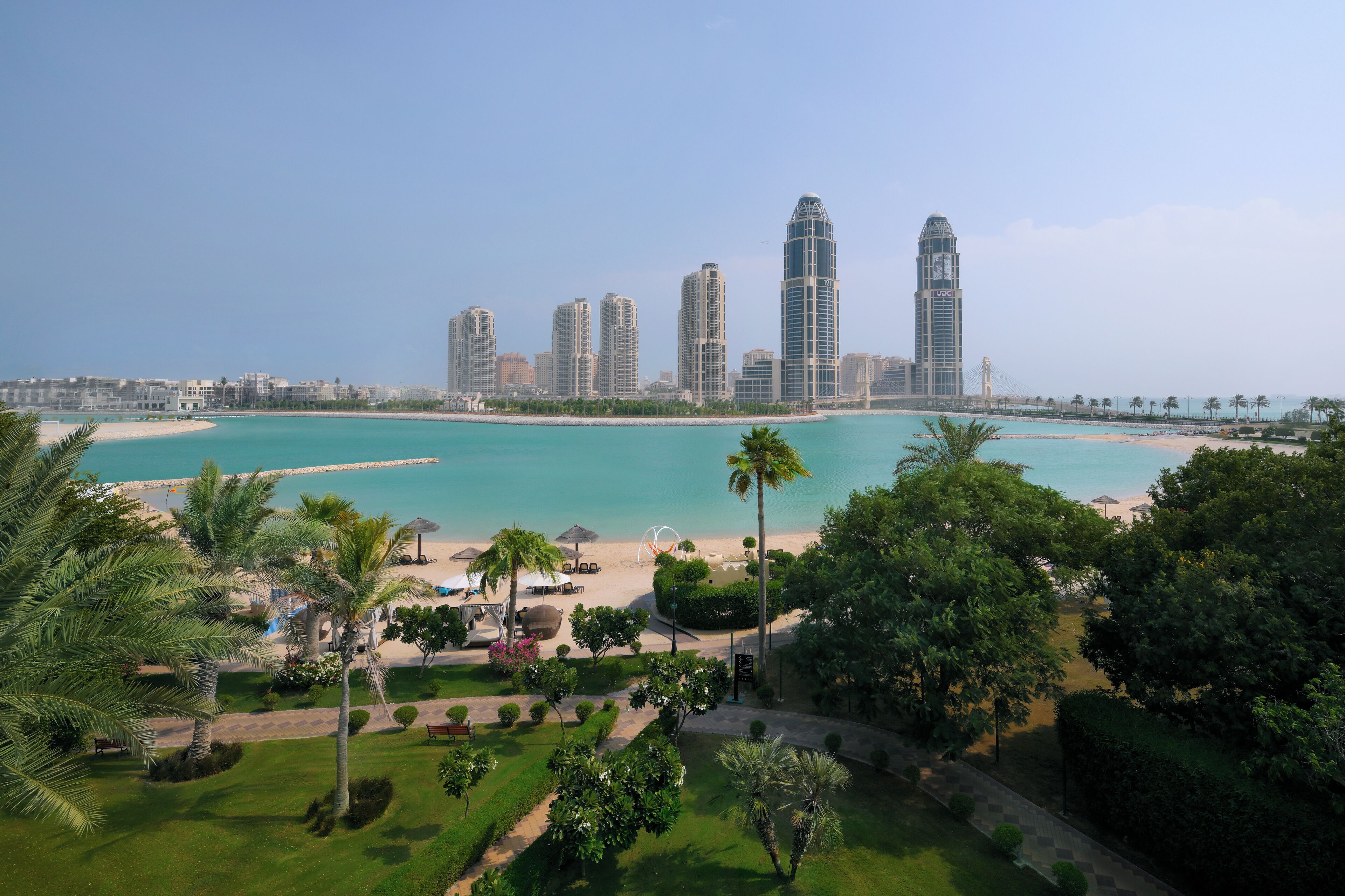 Un paisaje urbano costero con rascacielos, una playa y abundante vegetación.