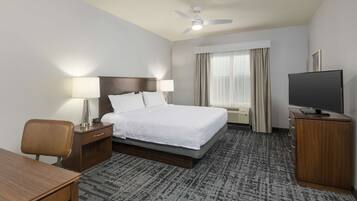 Habitación de hotel con cama, mesitas de noche, escritorio, televisor y ventilador de techo.