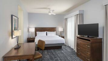Una habitación de hotel con cama, escritorio, silla, televisor y cómoda.