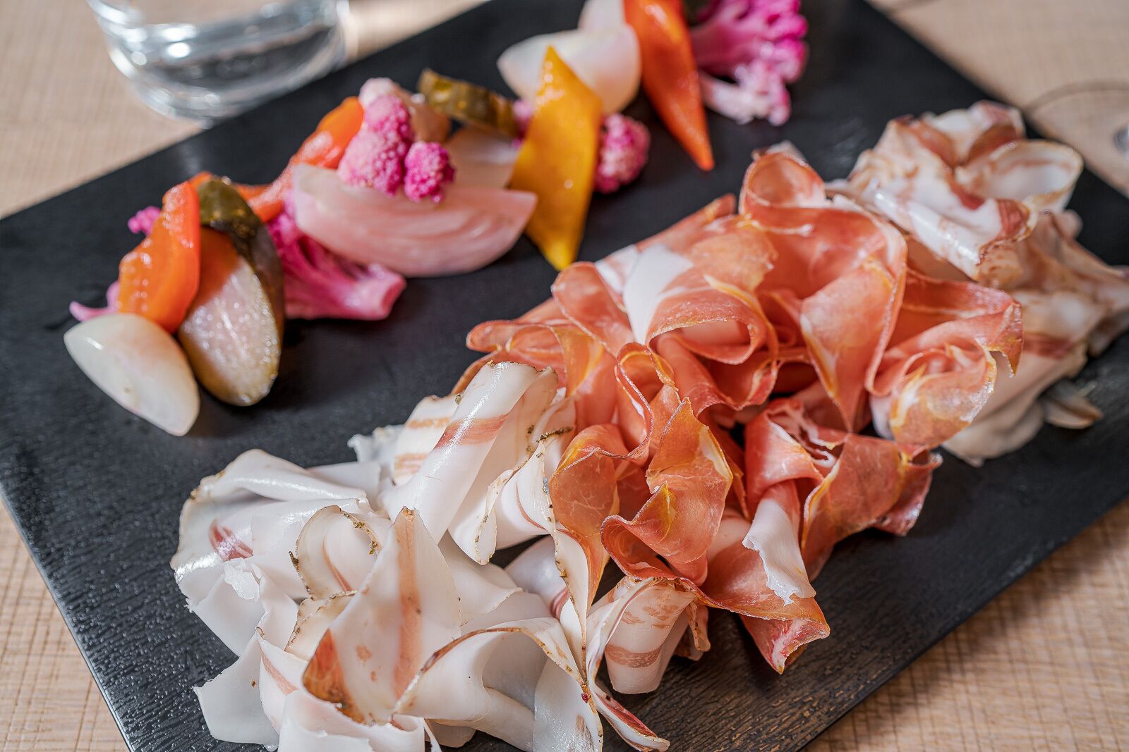 A charcuterie board with various meats and vegetables.