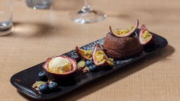 A dessert plate with a chocolate mousse, passion fruit halves, blueberries, and a scoop of ice cream.