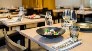 Un ambiente de restaurante con mesas dispuestas para comer, mostrando platos de comida y copas de vino.