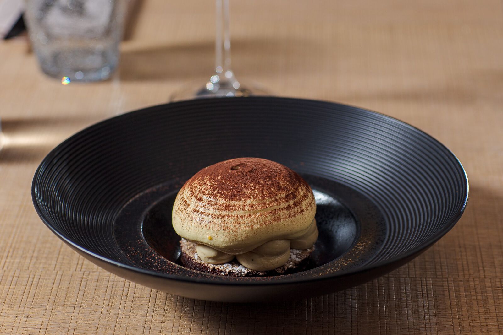 Un postre sobre un plato negro con superficie texturizada.