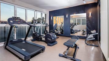 A modern gym with treadmills, elliptical machines, and free weights.