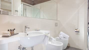 Un baño moderno con un lavamanos grande, dos lavabos, un inodoro y una zona de ducha.