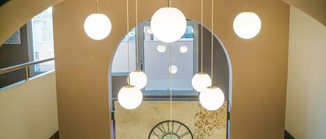 A modern interior with a large arched window, multiple hanging spherical light fixtures, and a wall clock.