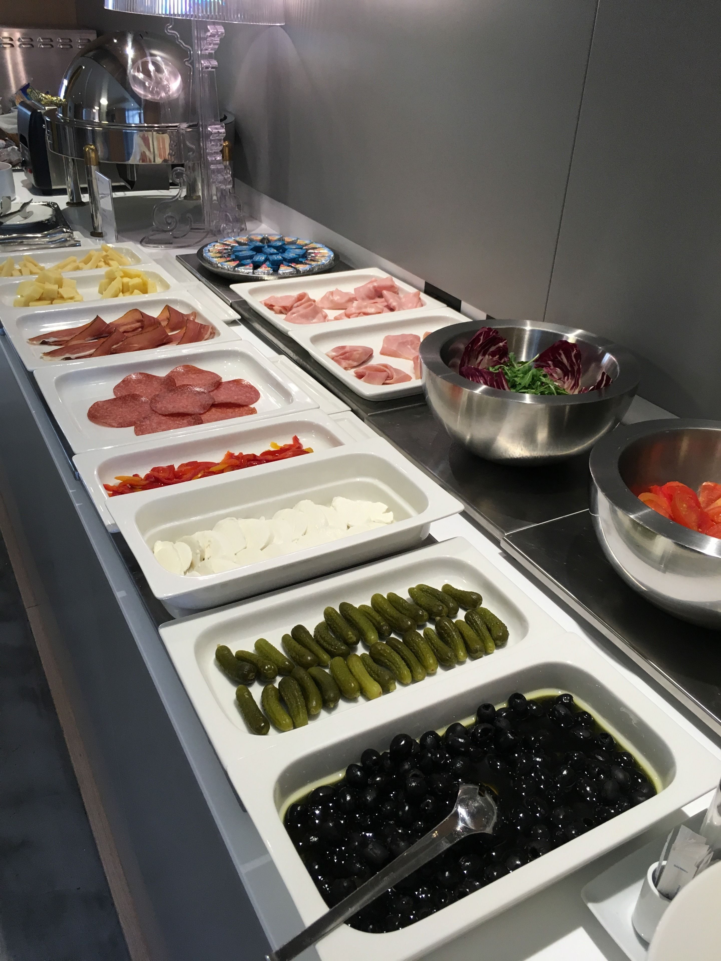 A buffet with various food items including meats, cheeses, vegetables, and olives.