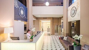 Un vestíbulo de hotel con mostrador de recepción, un sofá y una escalera.