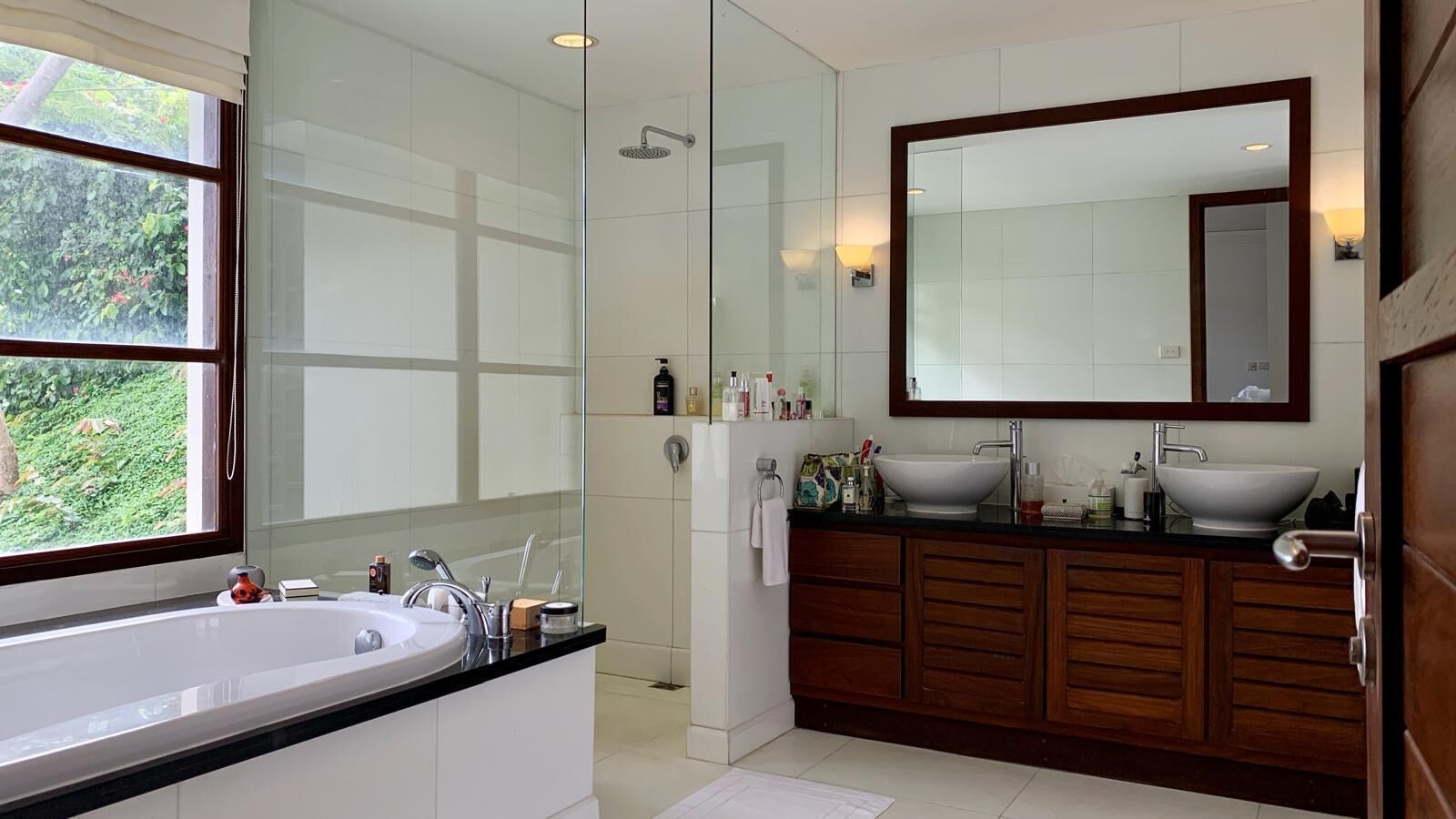 A modern bathroom with a large bathtub, a separate shower area, and a vanity with a large mirror.
