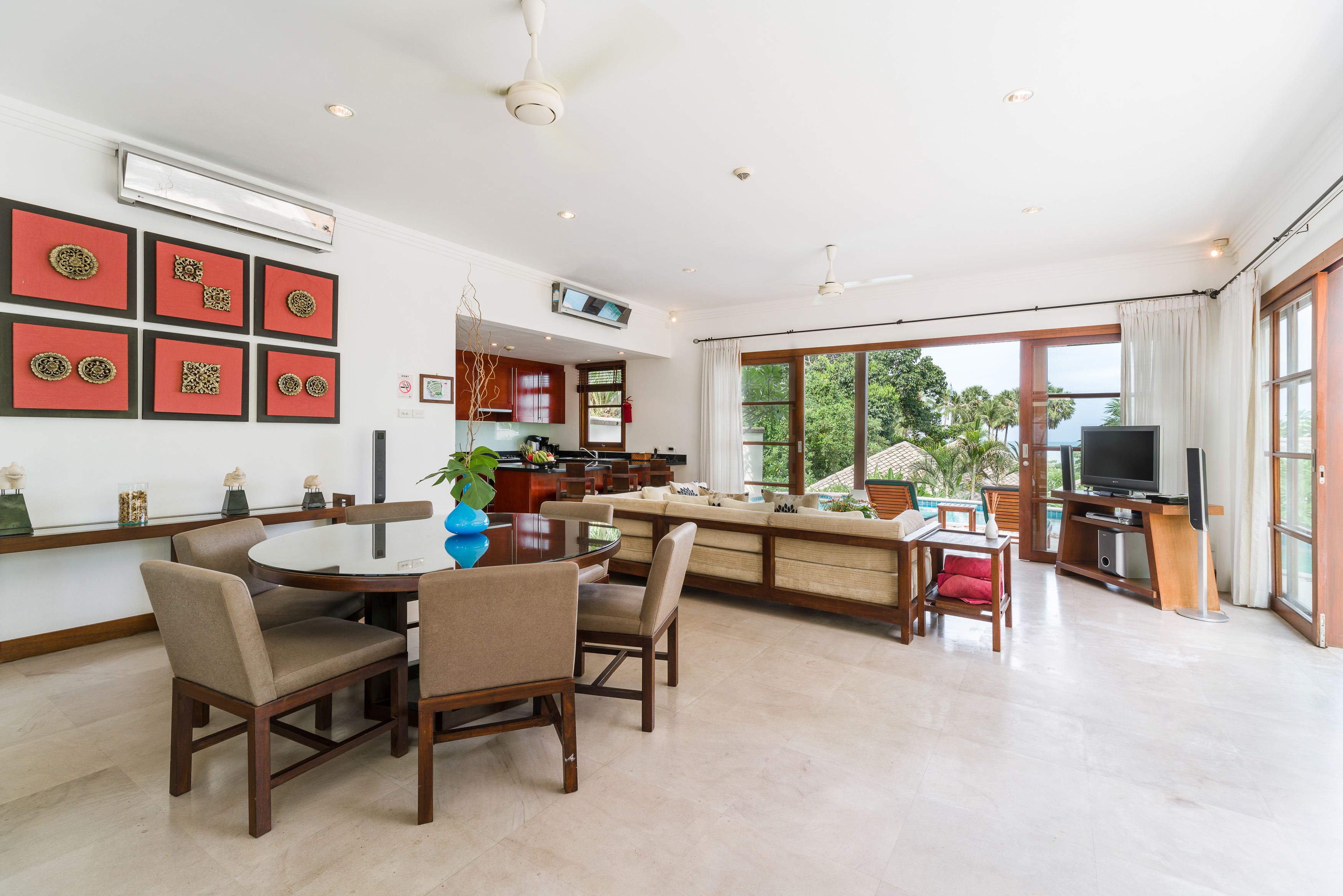 A modern kitchen with a dining area, large windows, and a TV.