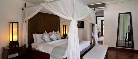 A four-poster canopy bed with a bench, bedside lamps, and decorative pillows.