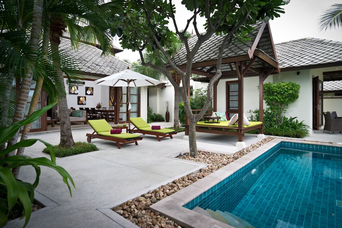 A poolside area with lounge chairs, a pergola, and a small pool.
