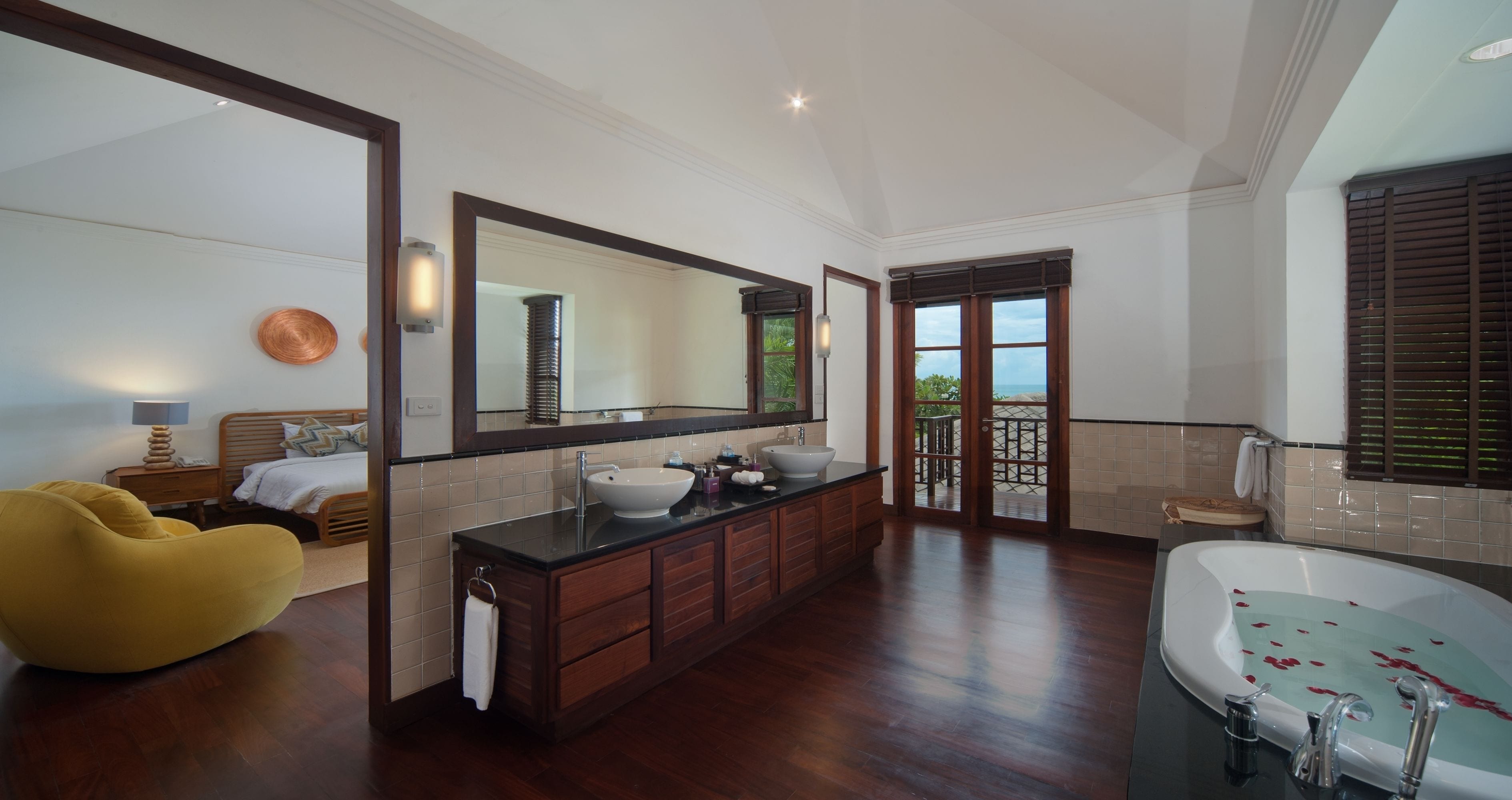 A spacious bathroom with a large mirror, a bathtub, and a vanity with a sink.