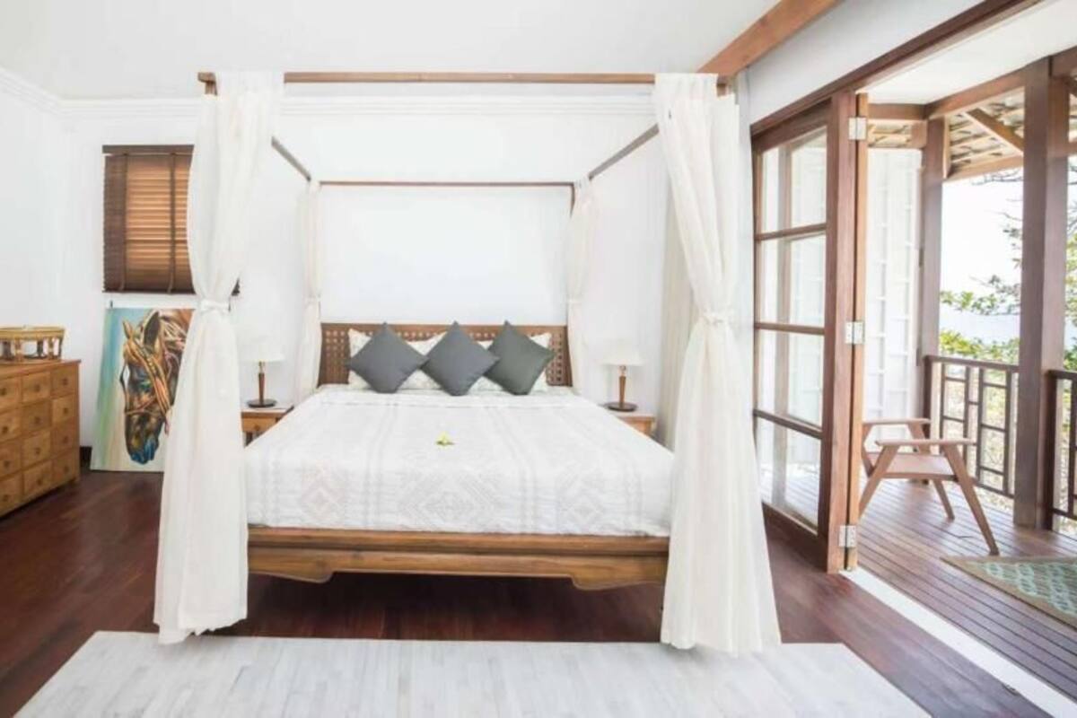 A four-poster bed with a canopy, wooden headboard, and two nightstands.