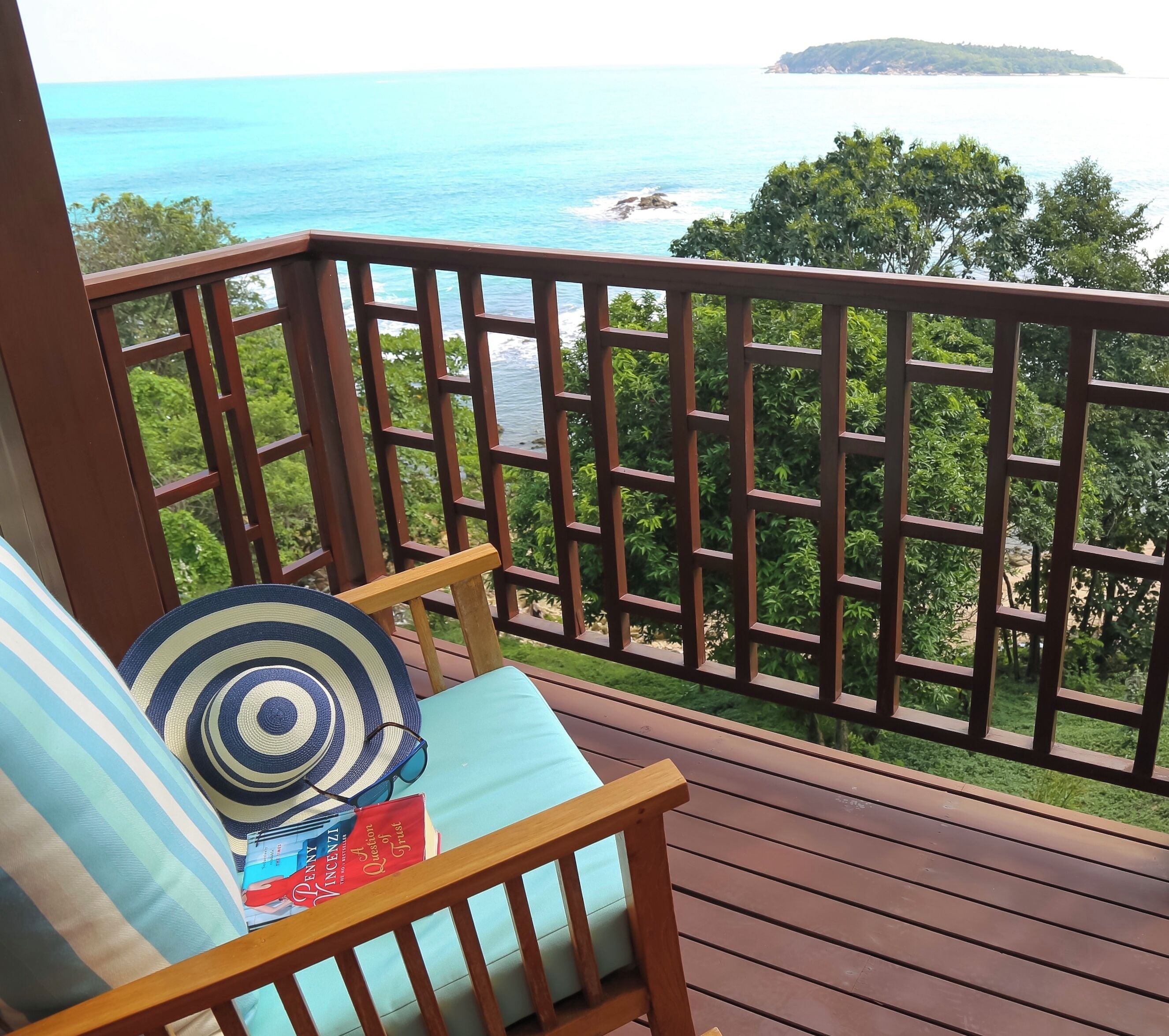 Une terrasse en bois offrant une vue sur l’océan et une île lointaine.