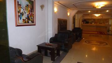 A lobby with leather armchairs, a coffee table, a painting on the wall, and a reception desk.
