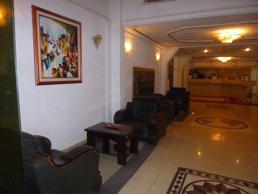 A lobby with leather armchairs, a coffee table, a painting on the wall, and a reception desk.
