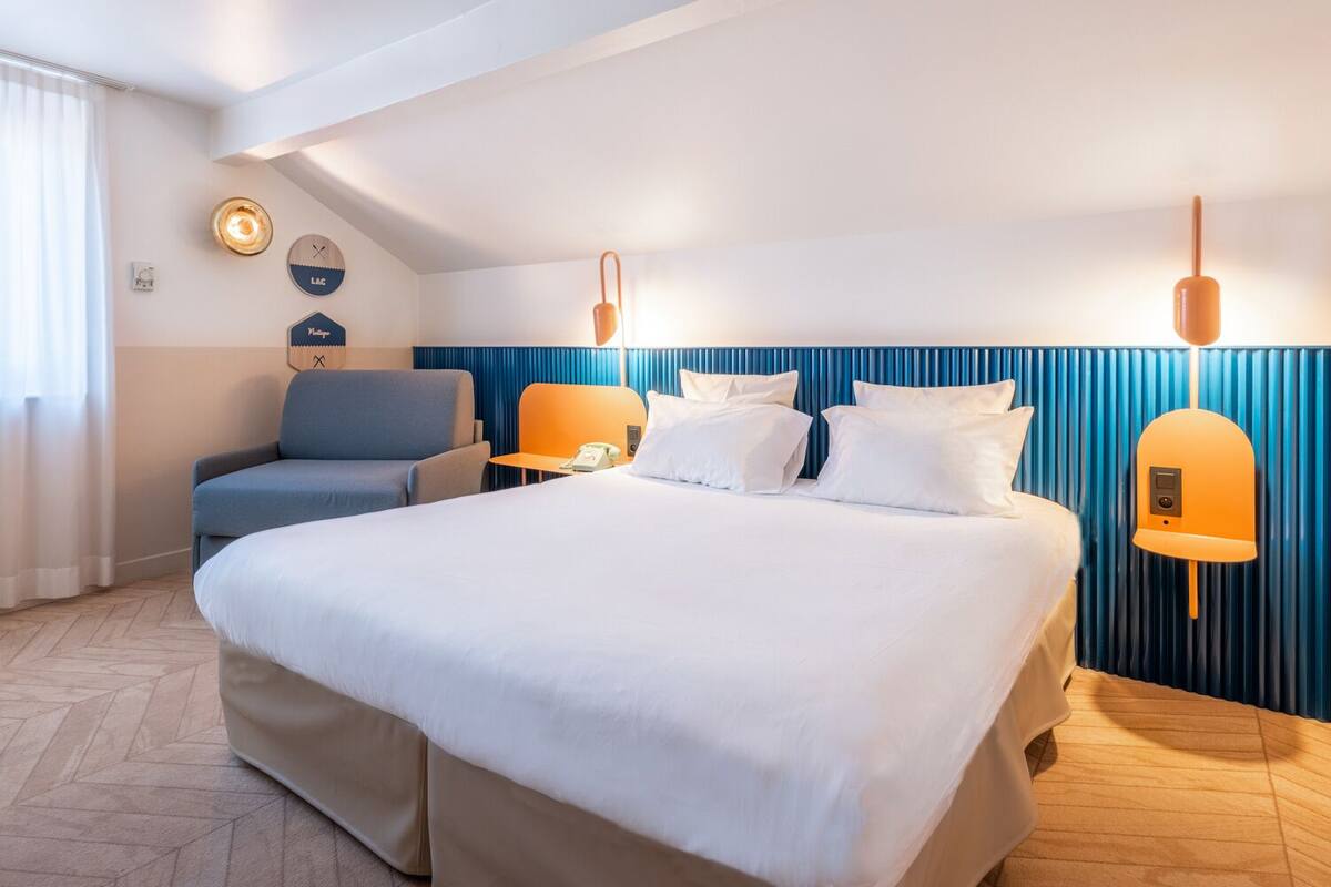 Une chambre d’hôtel avec un grand lit, un bureau, une chaise et un téléphone fixé au mur.