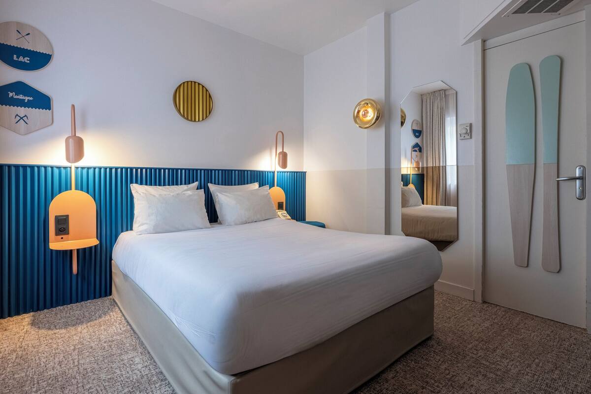 Une chambre d’hôtel avec un grand lit, un miroir, une horloge et une porte décorée sur le thème du ski.