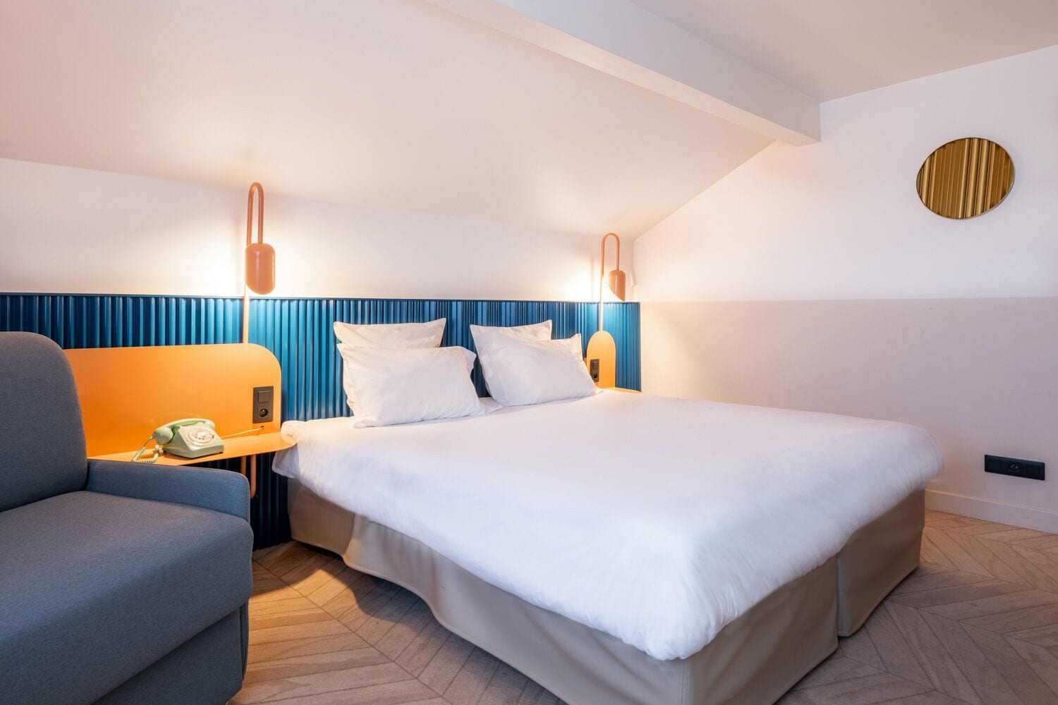Ein modernes Hotelzimmer mit einem großen Bett, einem Nachttisch mit Telefon und einer blauen Akzentwand.