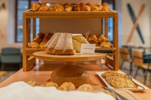 A buffet table with a variety of pastries and a sign indicating 'Gâteau de Savoie'.