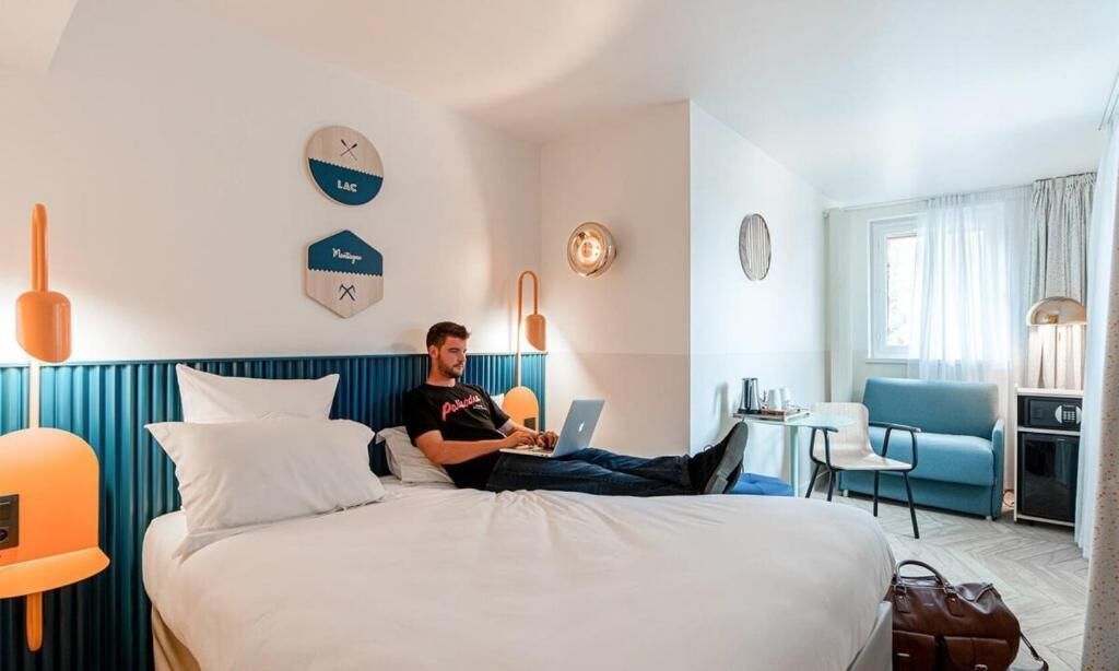 Una habitación de hotel con cama, escritorio, silla y ventana.