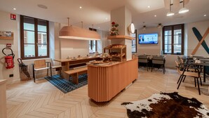 A modern kitchen with a central island, wooden furniture, and a television mounted on the wall. - Hôtel du Palais de l'Isle (Annecy)