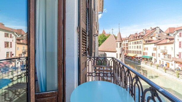 A balcony with a view of a river and buildings. - Hôtel du Palais de l'Isle (Annecy)