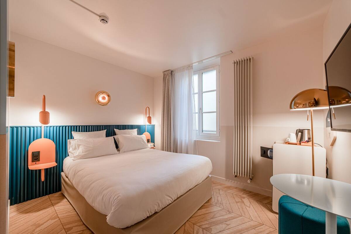 Une chambre d’hôtel moderne, dotée d’un grand lit, d’un bureau et d’une fenêtre avec des rideaux.