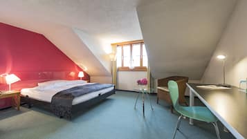 Une chambre à coucher comprenant un lit, une table de chevet, une lampe, une chaise et une petite table sur laquelle est posé un vase.