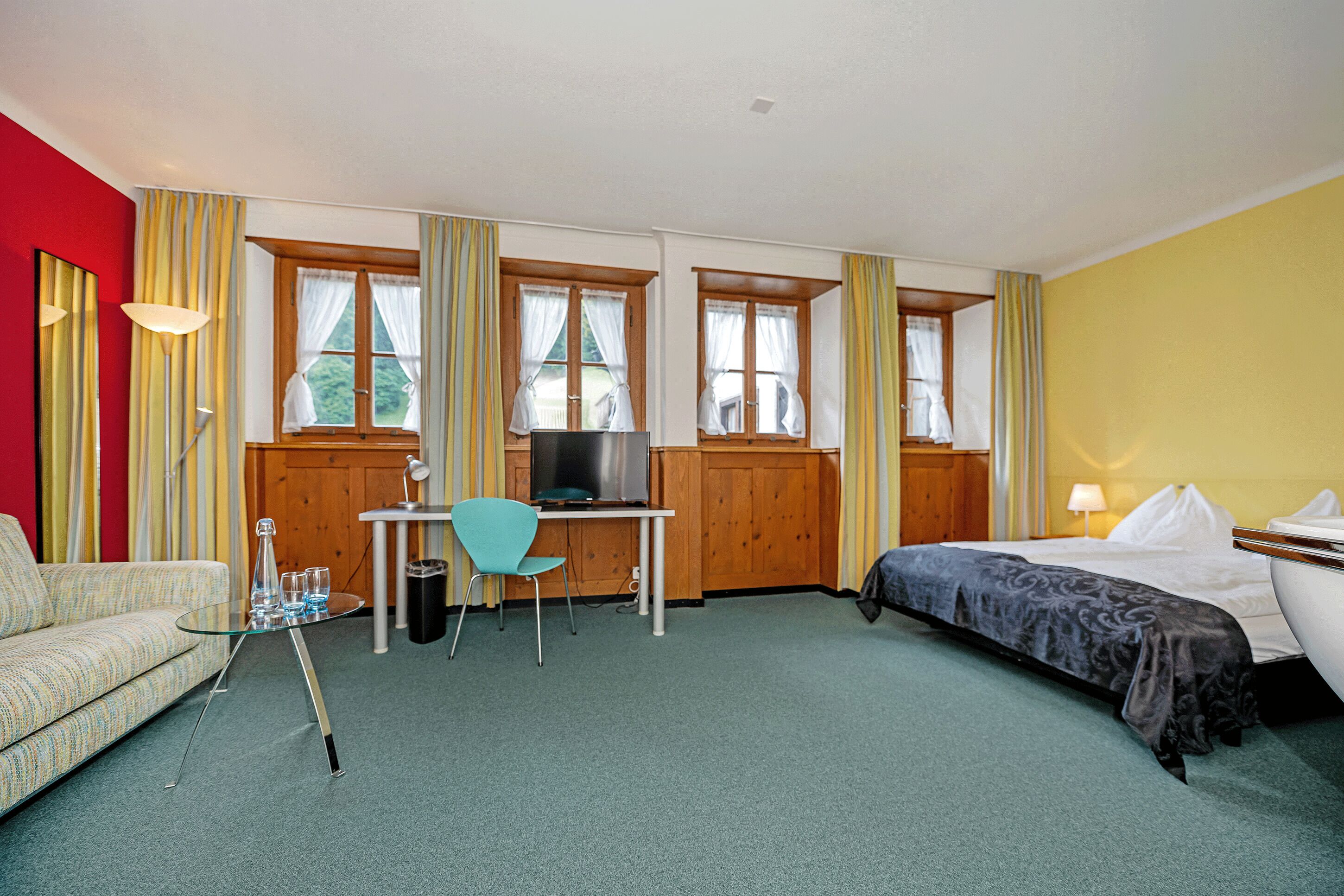Una habitación de hotel con una cama, un escritorio con computadora, una silla y un sofá.