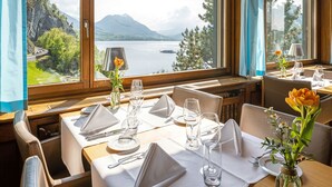 A dining table set for two with a view of a lake and mountains. - See- und Seminarhotel FloraAlpina (Vitznau)