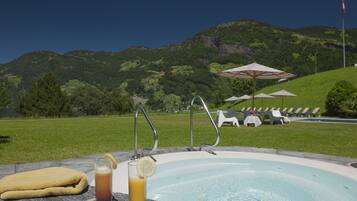 Zona de piscina con una limonada, una toalla y sillones de playa con sombrillas.