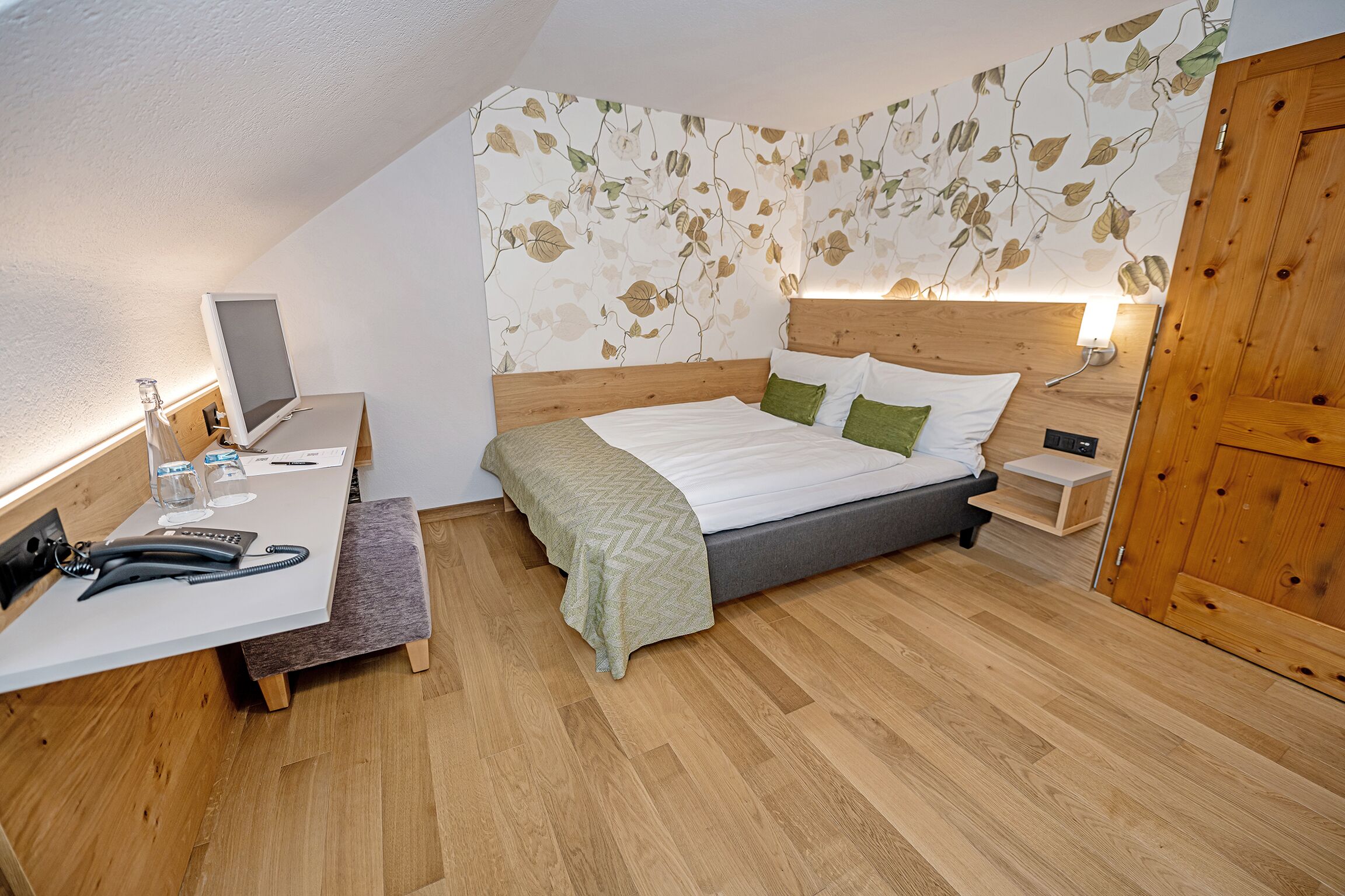 A bedroom with a bed, bedside tables, a desk, and a telephone.