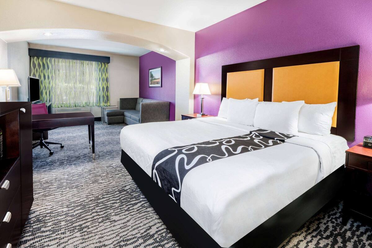 Ein Hotelzimmer mit einem großen Bett, einem Schreibtisch, einem Stuhl und einer Couch.