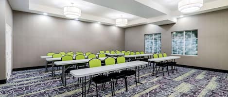 Una sala de conferències amb taules i cadires, grans finestres i una catifes amb disseny.