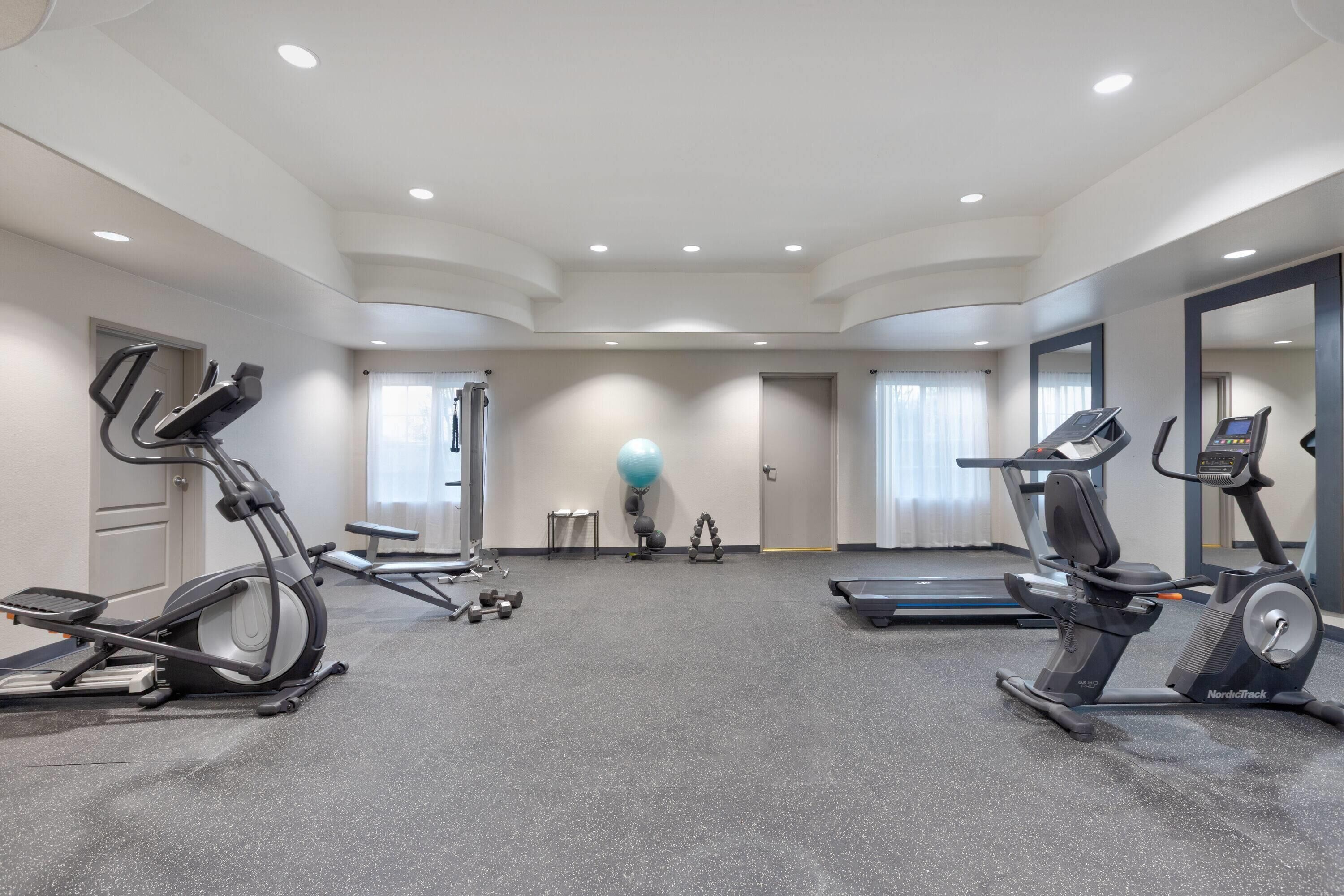 A gym with treadmills, elliptical machines, and free weights.