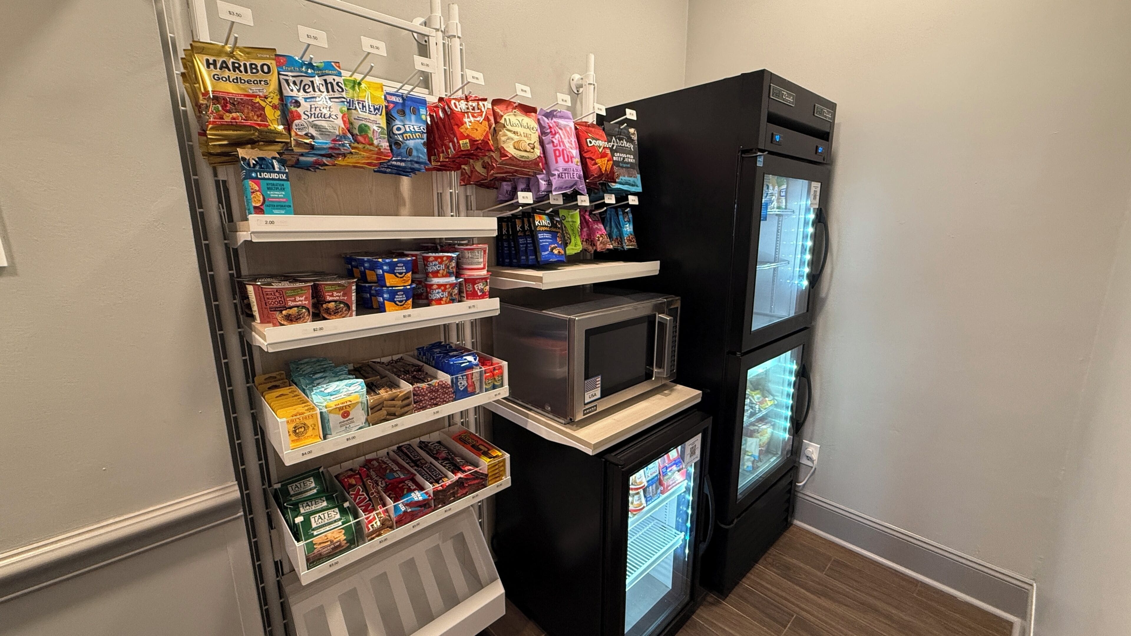 A compact kitchen with a refrigerator, microwave, and a small freezer.