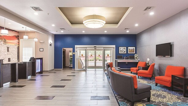 A hotel lobby with a reception desk, seating area, and a television. - La Quinta Inn & Suites by Wyndham San Antonio Northwest (San Antonio)
