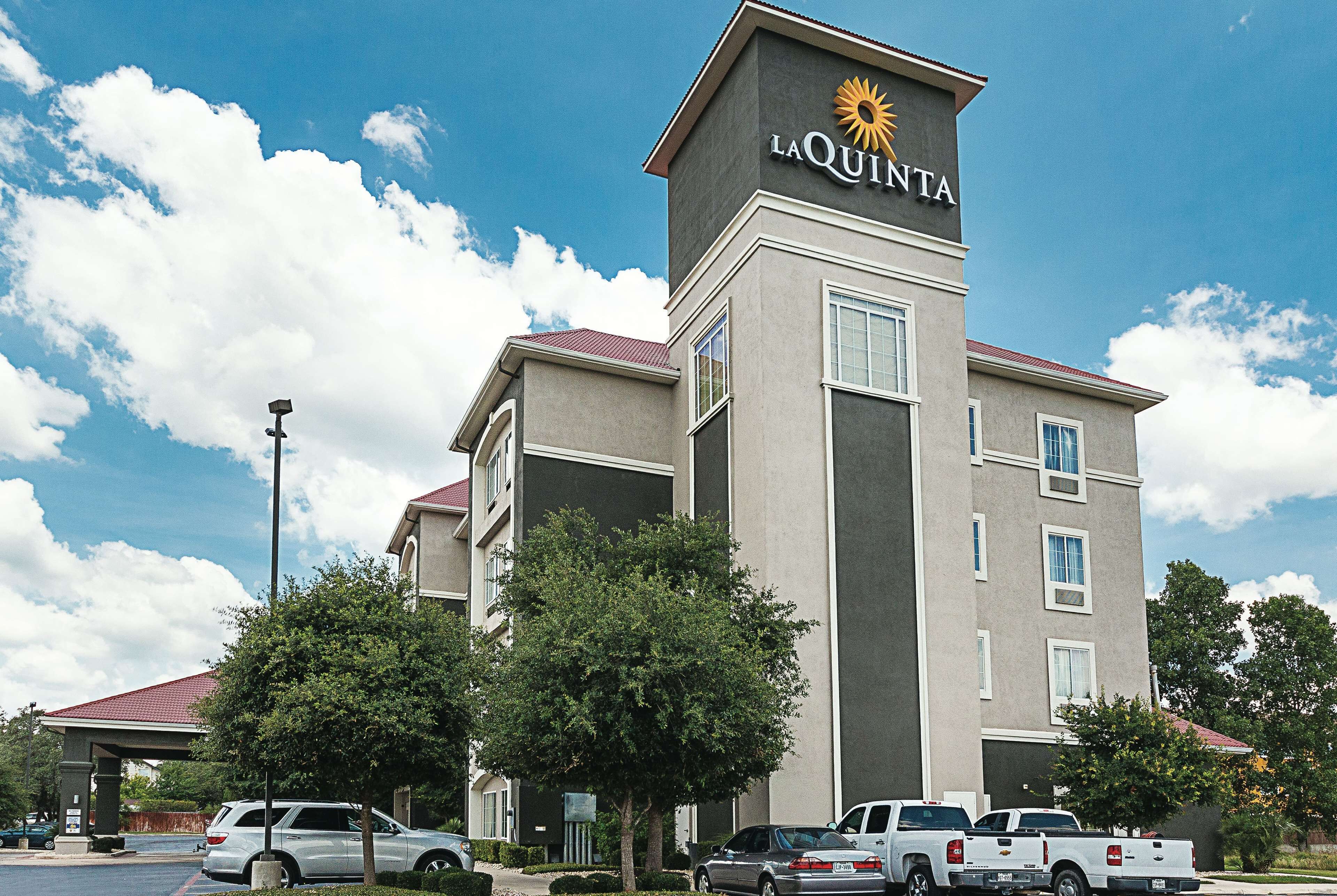 A La Quinta hotel with a prominent sign, parking area, and surrounding greenery.