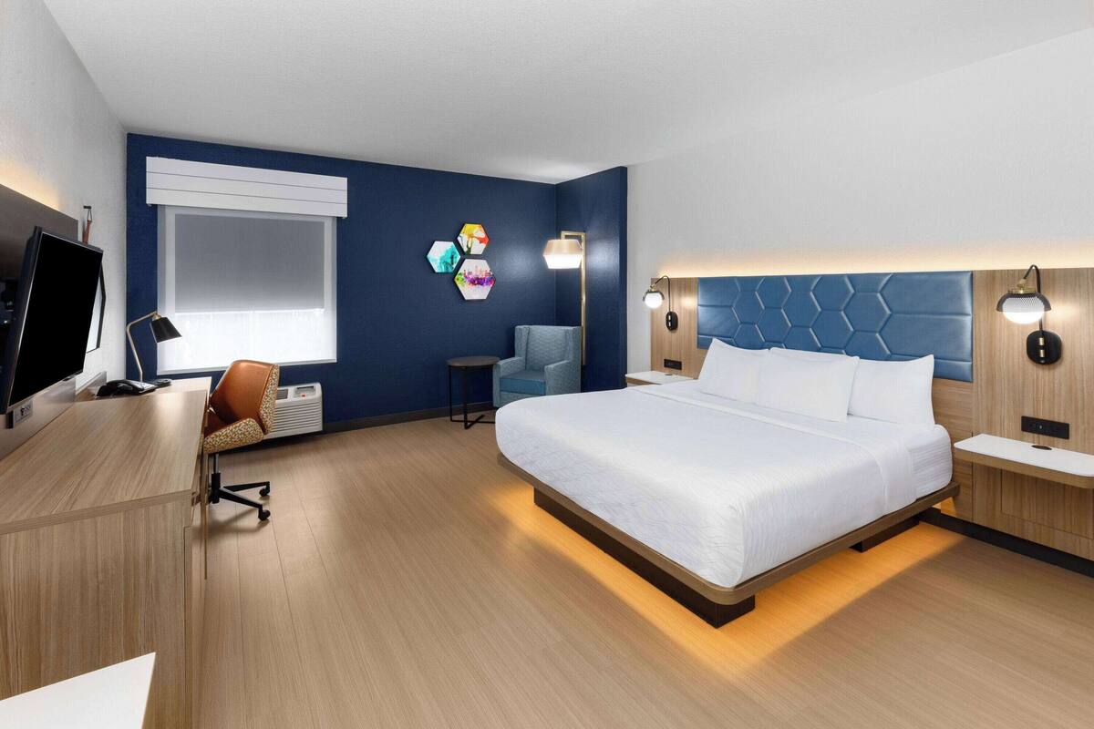 Une chambre d’hôtel moderne avec un grand lit, un bureau équipé d’un ordinateur, une chaise et un téléviseur.