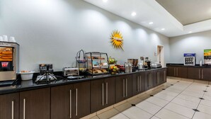 A breakfast bar with a coffee machine, toaster, and fruit display.